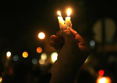 A woman holds candles during a vigil held for the victims of ...