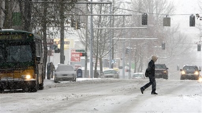 A pedestrian crosses snow covered Stewart Street in downtown ...