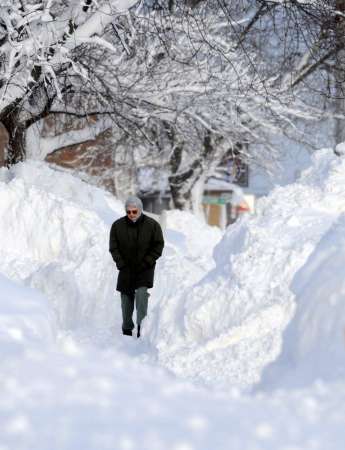 A woman negotiates her way through snow drifts after a snowstorm ...